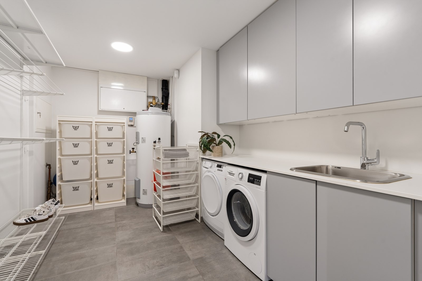 Romslig vaskerom fra byggeår som har fliser på gulv og malte, slette vegger. Rommet har innredning med laminat benkeplate, utslagsvask og opplegg for vaskemaskin. Galleribilde