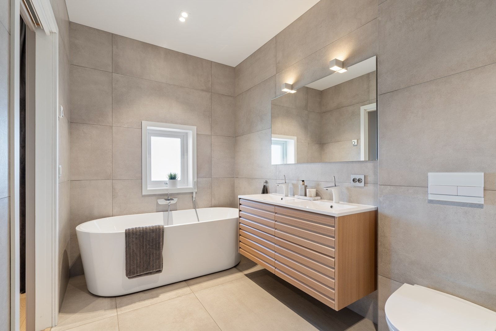 Det lekre badet er moderne utført med store, lekre fliser på både gulv og vegger. Galleribilde