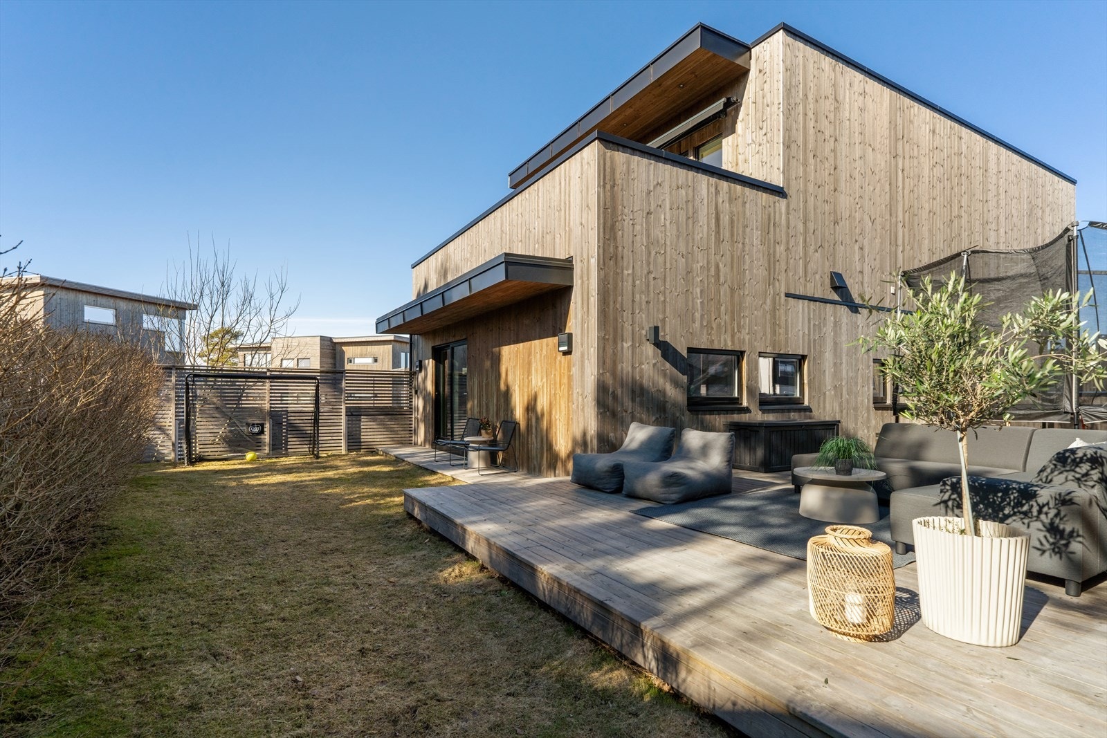 Her kan du nyte sommeren fine dager i en usjenert hage som er pent opparbeidet med treplatting, gressplen, hekk og levegg. Galleribilde