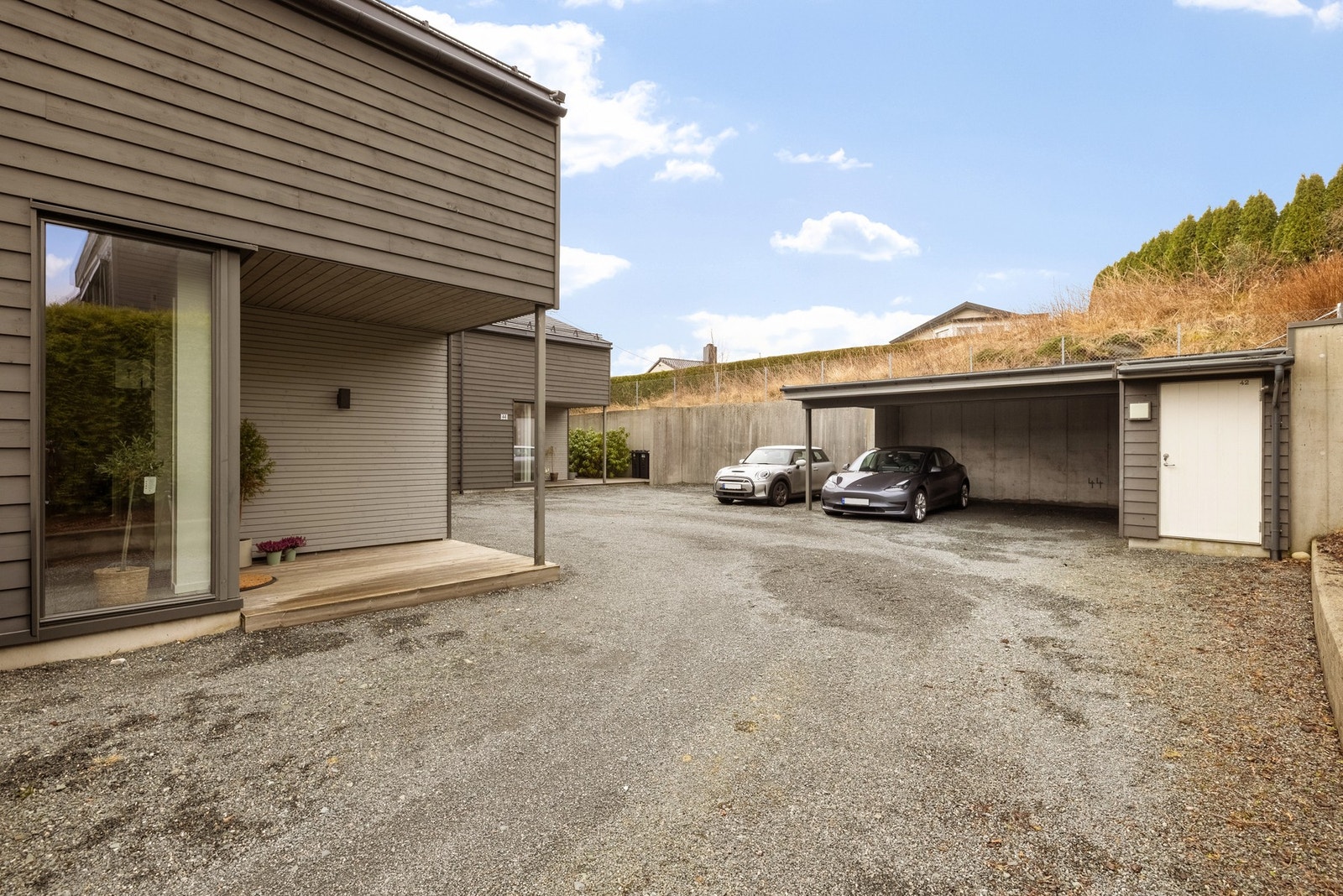 Boligen har en parkeringsplass i carport og en ved siden av, samt lader til el-bil. Galleribilde