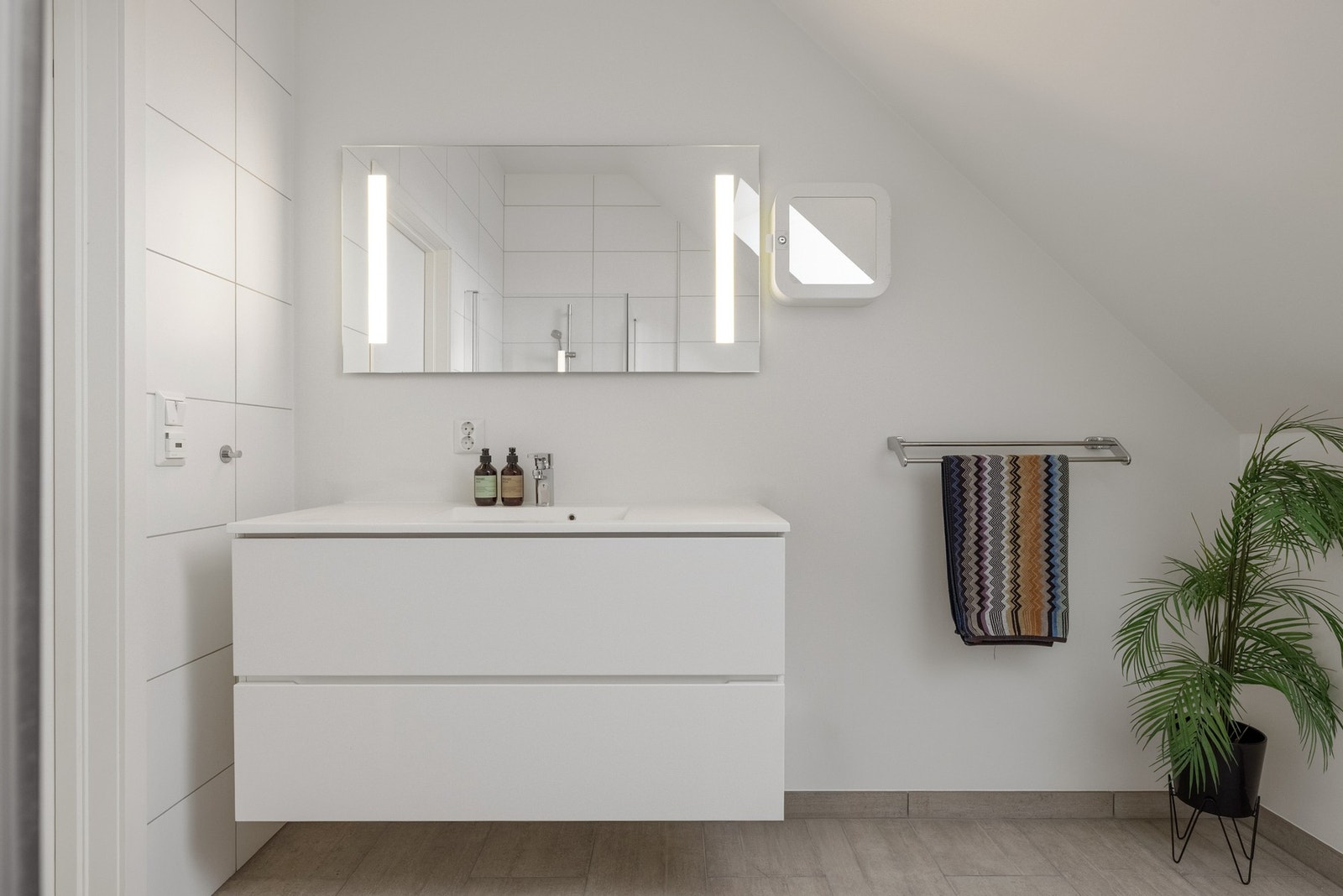 Det er innredet med vegghengt toalett, dusjhjørne med dusjgarnityr og møblement med speil og belysning. Galleribilde