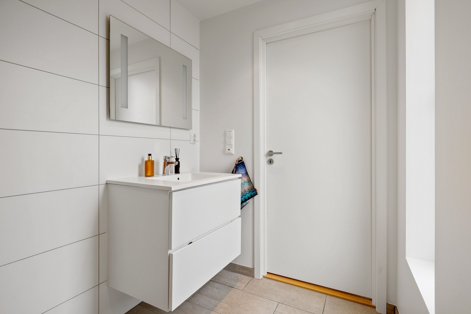 Badet er flislagt på gulv og delvis på vegg, hvor det også er malt platekledning, samt innfelte spotlights i himling. Varmekabler i gulv. Galleribilde