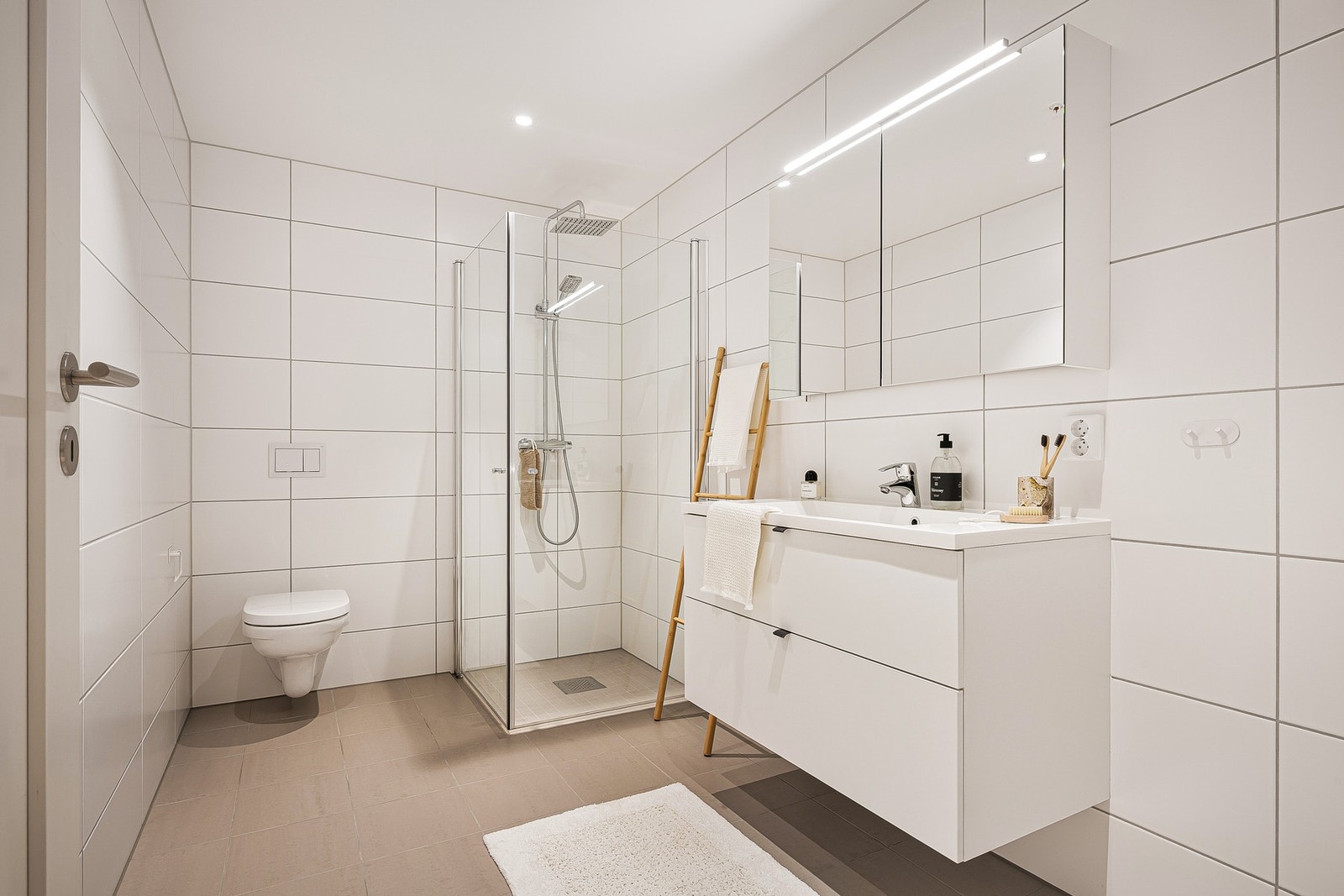 -Badet består av vegghengt toalett, dusj, servant, speil og belysning. - Galleribilde