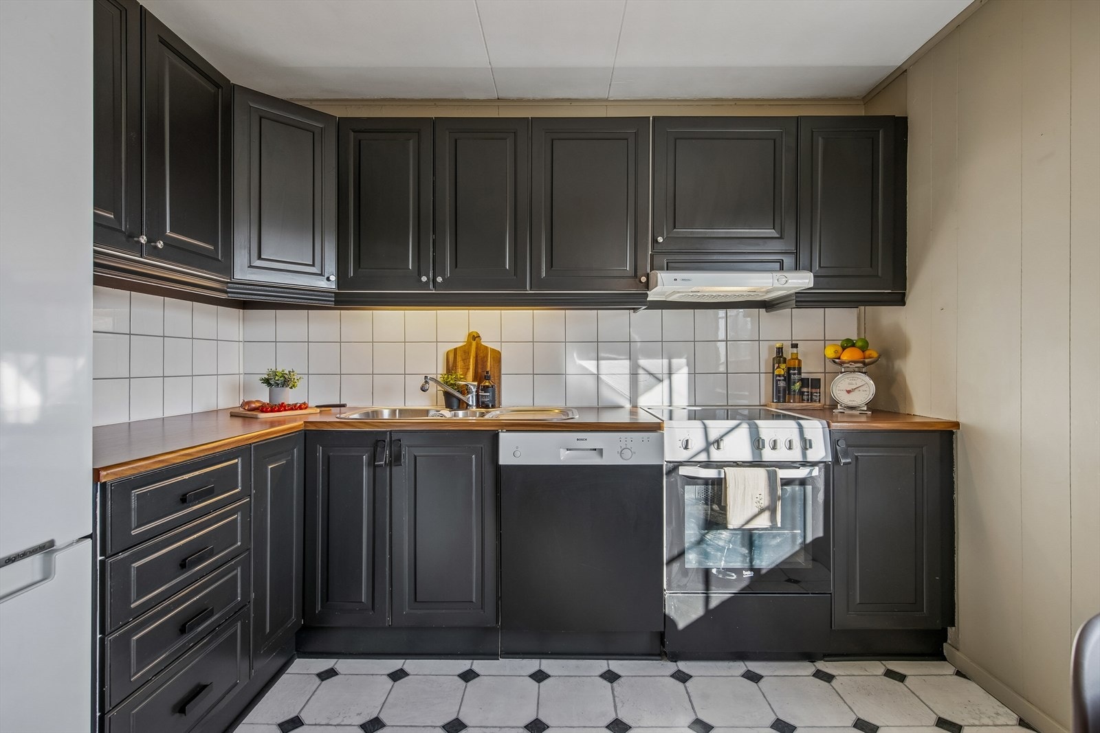 Kjøkkeninnredningen har malte, profilerte fronter, laminatbenkeplate og fliser over benken. Galleribilde