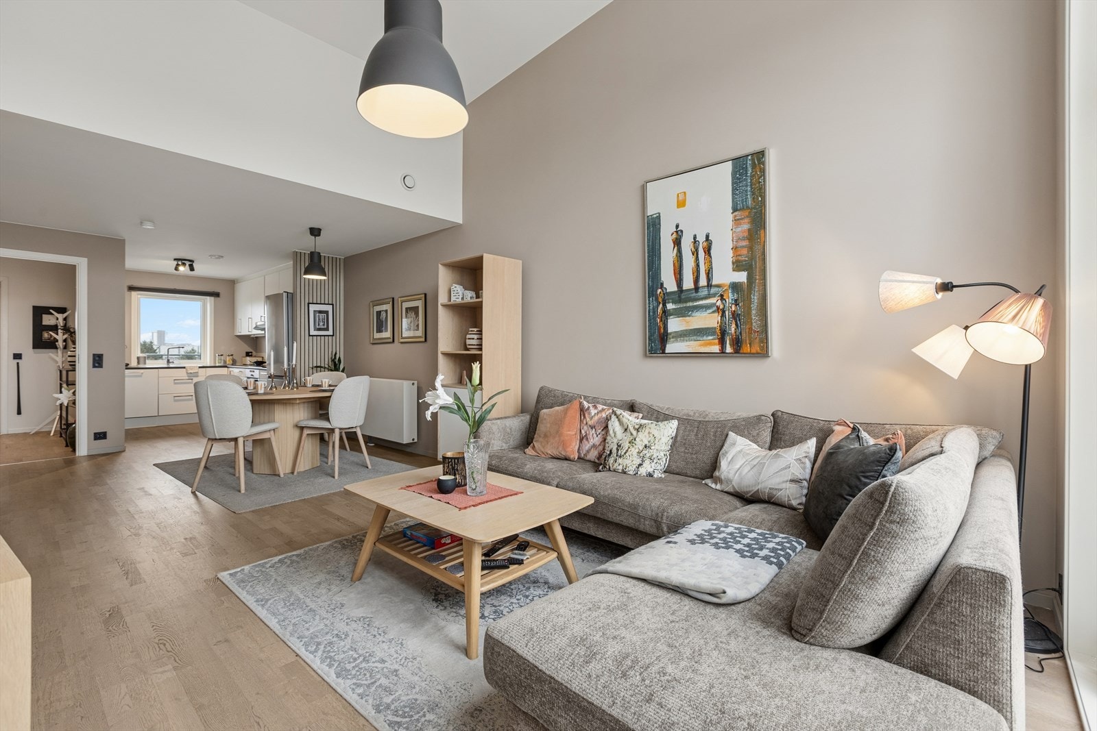 Leilighetens sosiale sone med stue og kjøkken ligger i åpen løsning. Et lyst og innbydende rom med store vindusflater som slipper inn rikelig med naturlig lys og sammen med den ekstra gode takhøyden gir en god romfølelse. Galleribilde