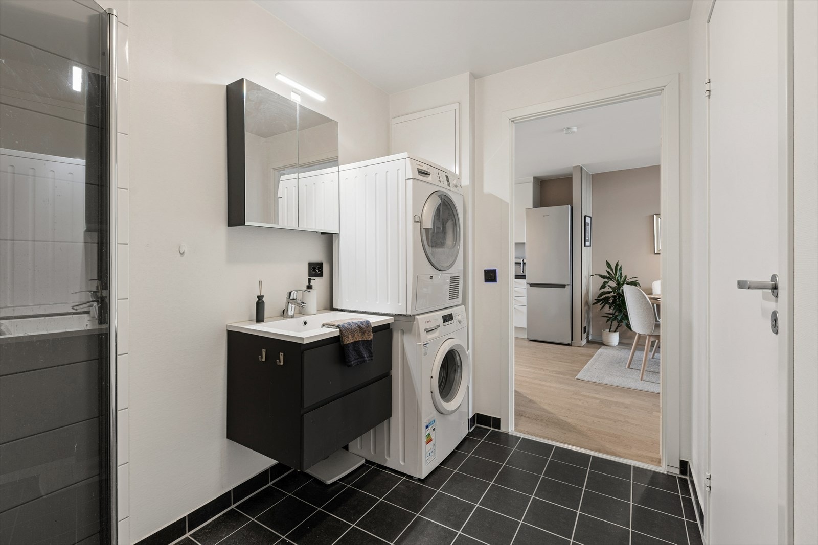 Badet er ellers utstyrt med stort dusjhjørne, toalett og baderomsinnredning med god lagringsplass og nedfelt servant. I tillegg har man opplegg for vaskemaskin og plass til tørketrommel. I bakkant av badet har man en bod som gir ekstra lagringsplass. Galleribilde