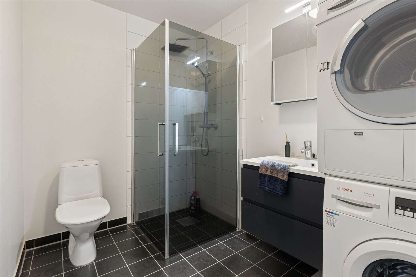 Badet er tidløst innredet med grå fliser på gulvet og en kombinasjon av hvite fliser på vegg i dusjsone og ellers lysmalte veggflater. I gulvet har man vannbåren varme for ekstra komfort. Galleribilde