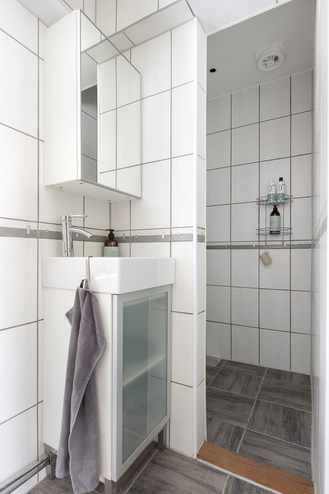 Det er fliselagt baderom som er innredet med servant nedfelt i servantskap, veggskap med speilfront, Jets vegghengt vakuumtoalett og dusjhjørne Galleribilde