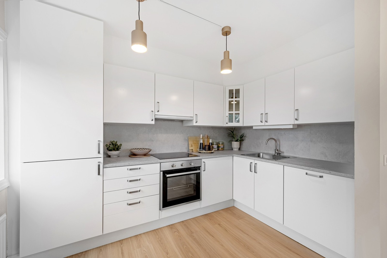Overflater fremstår moderne med hvite, glatte fronter og en laminat benkeplate med integrert vask. Galleribilde