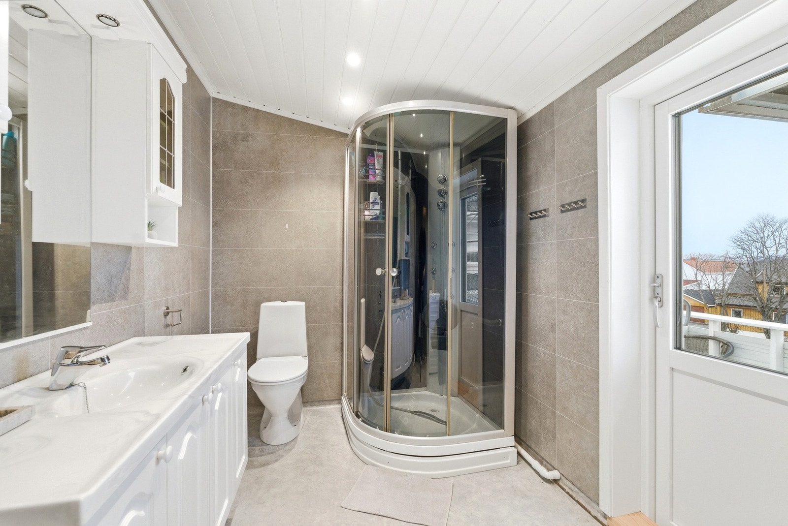 Badet er innredet med en praktisk innredning, dusjkabinett, toalett og opplegg for vaskemaskin. Galleribilde
