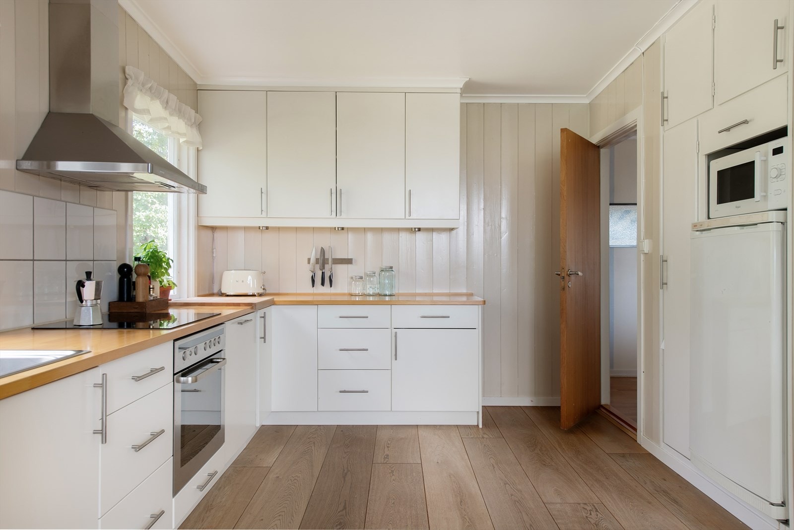 Innredning med lyse, glatte fronter og heltre benkeplate med oppvaskkum i stål. Galleribilde