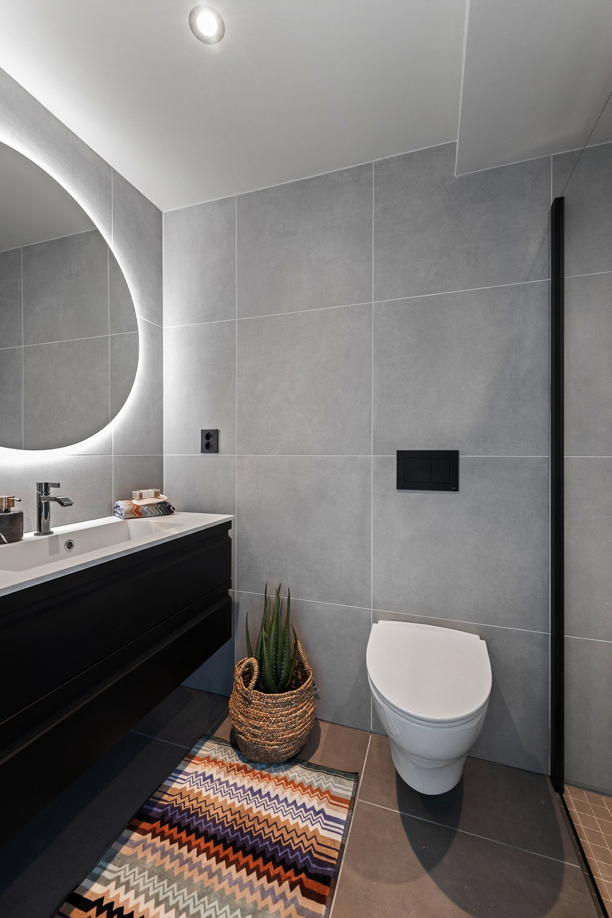 Badet er innredet med store, moderne fliser og sort garnityr. Galleribilde