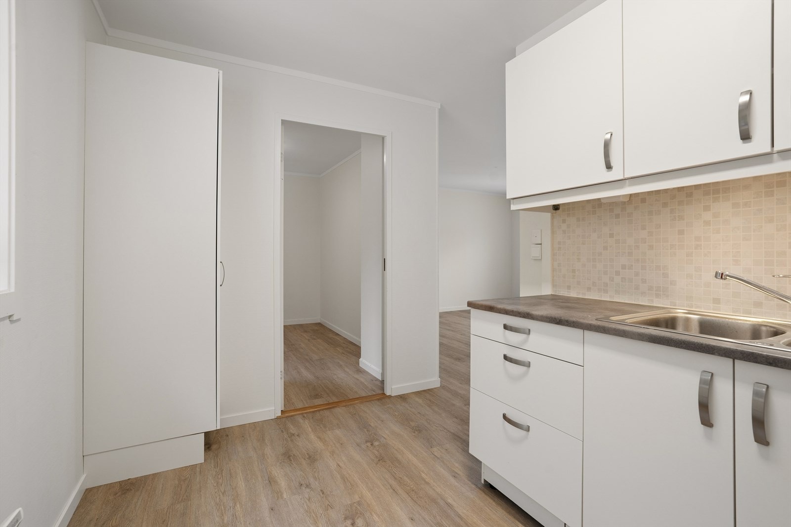 Kjøkkenet har innredning med glatte hvite fronter, laminat benkeplate og vannstoppsystem Galleribilde