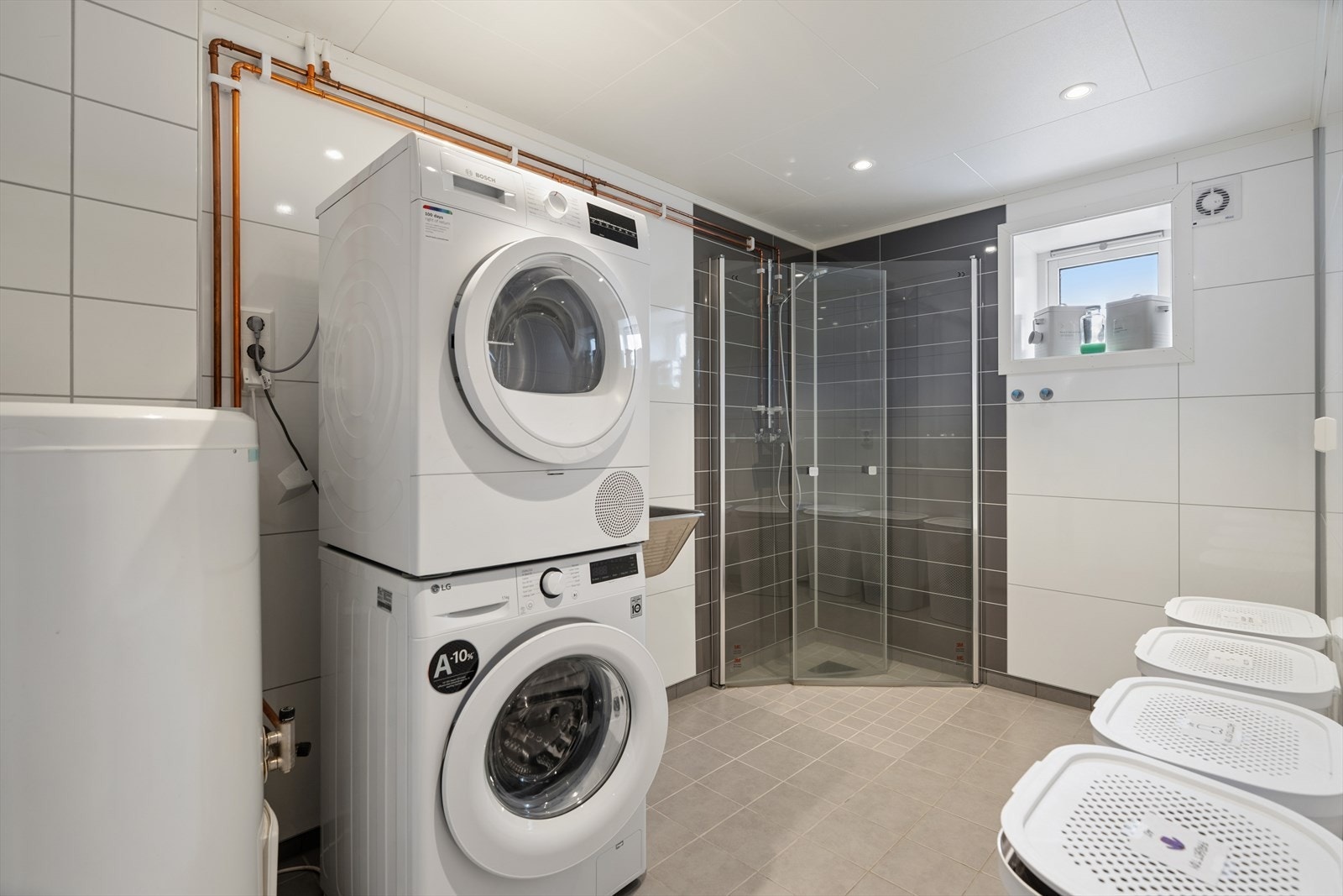 I kjelleren finner du et praktisk bad/vaskerom. Rommet har flislagt gulv med elektriske varmekabler som gir god varme og komfort. Veggene er kledd med en kombinasjon av fliser og våtromsplater, noe som gir et funksjonelt og lettstelt våtrom. Galleribilde