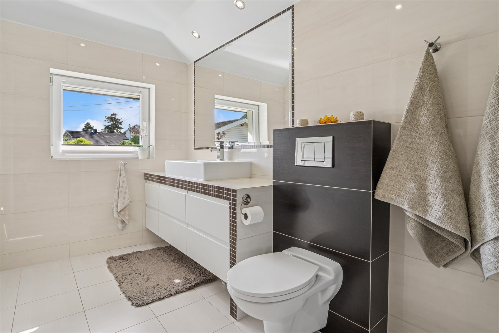 Baderommet er innredet med servant over innredning, speil og vegghengt toalett. Galleribilde