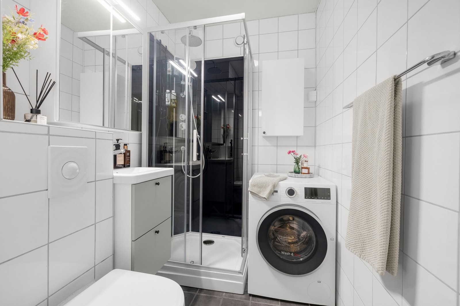 Badet har fliser på vegger og gulv, med komfortabel elektrisk gulvvarme. Her er det dusjkabinett og praktisk opplegg for vaskemaskin. Galleribilde