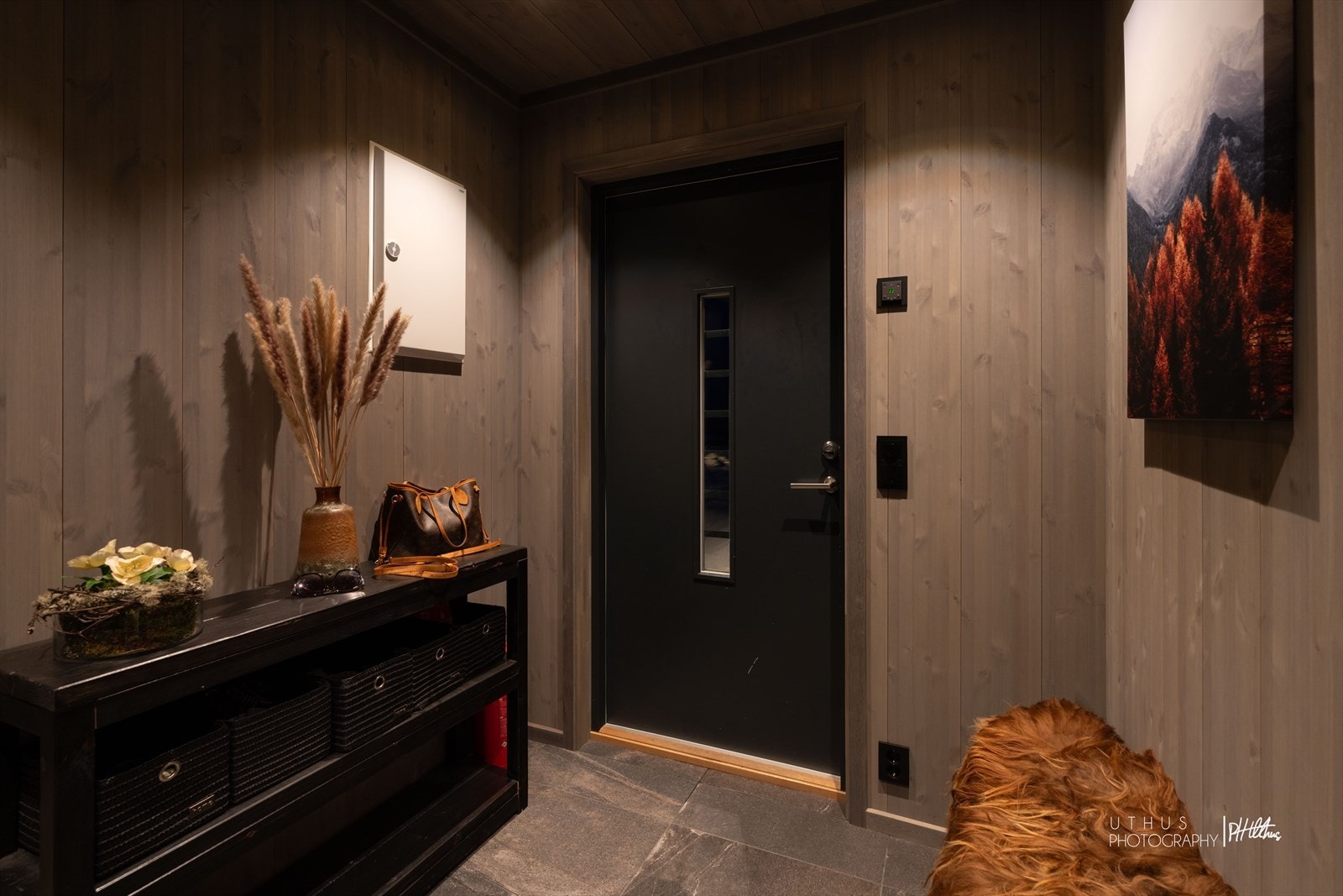 Gjennomgående bruk av beiset panel og en mørk fargepalett skaper en lun atmosfære. Galleribilde