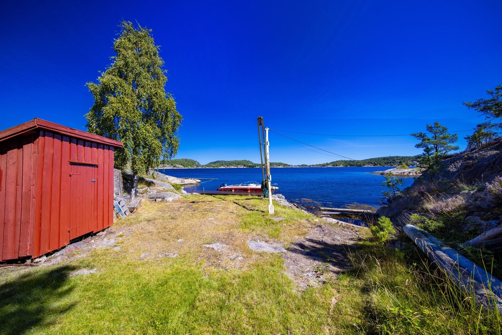 Brygge og sjøbod nordøst på eiendommen ved Fastersbukt, med Badeholmen utenfor. Galleribilde