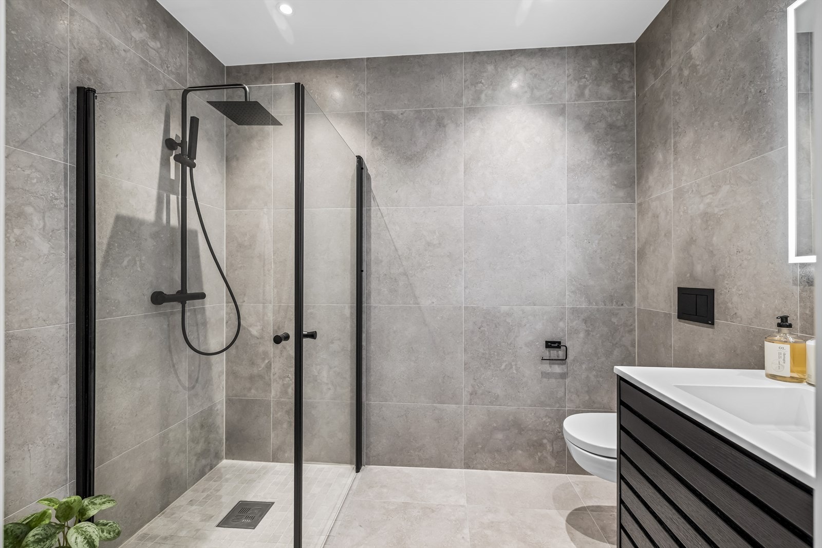Badet i 1. etasje har et moderne uttrykk med en stilren innredning i mørke kontraster. Galleribilde