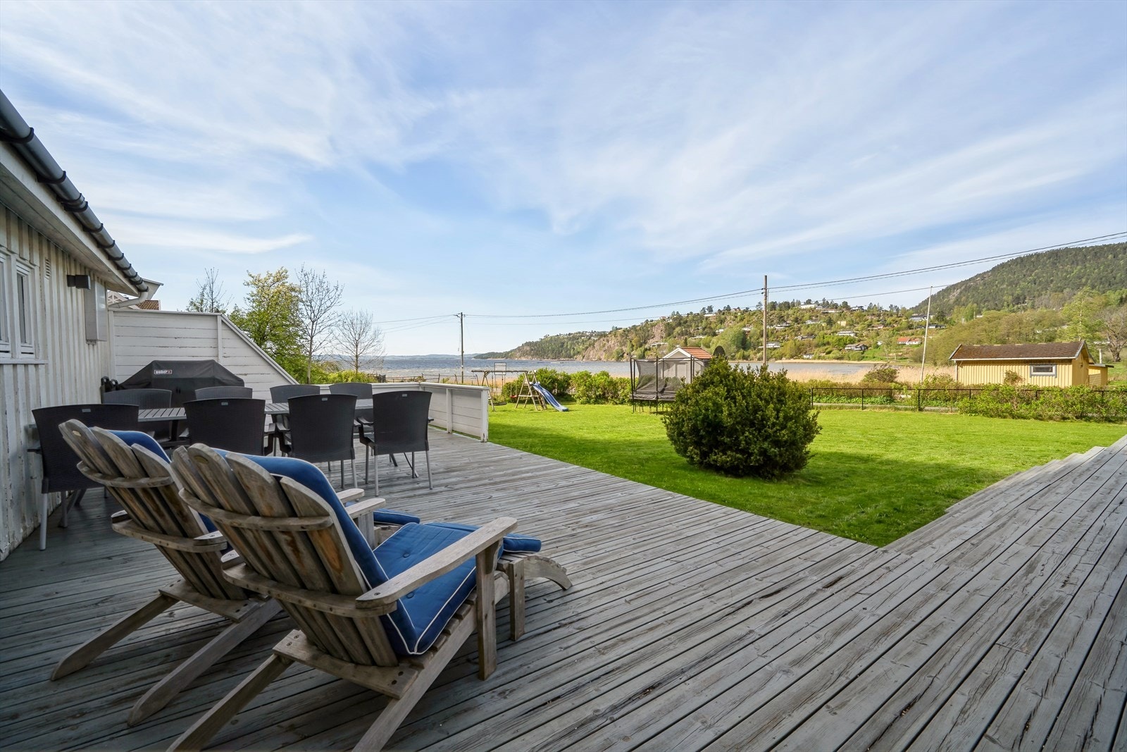 En solfylt plass med pen utsikt over hage og sjø, komplett med en idyllisk badestrand. Perfekt for avslappende dager. Galleribilde