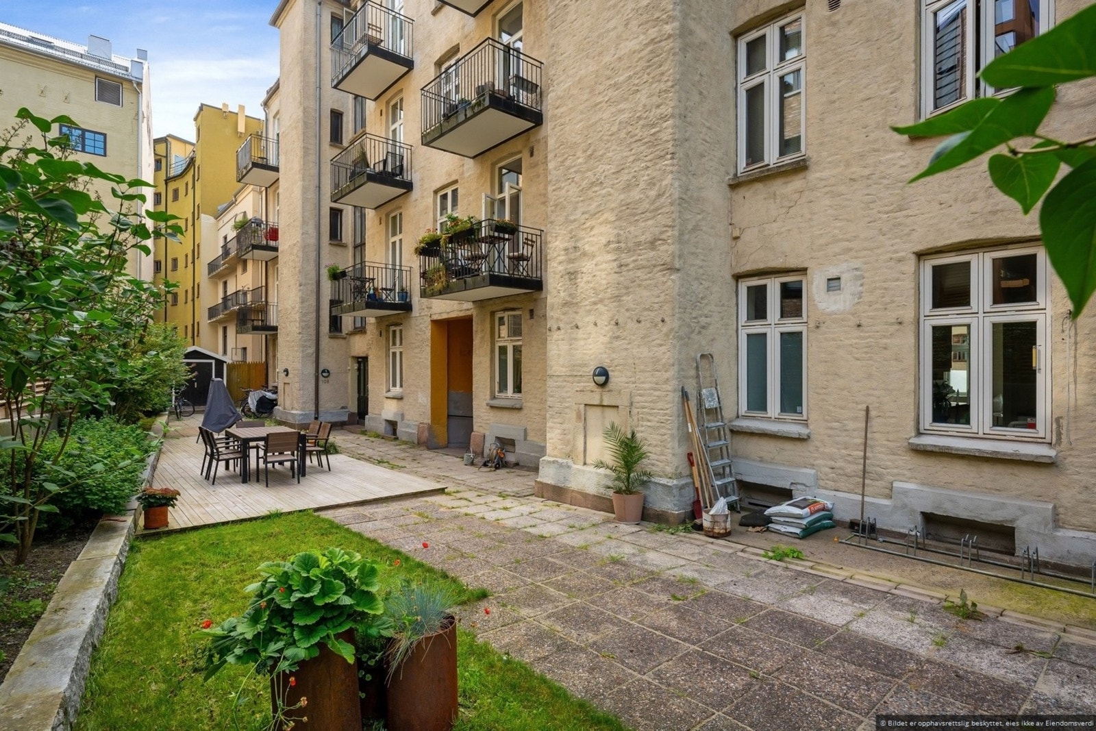 Hyggelig bakgård med beplantning og en felles sitte-platting med møblement, Galleribilde