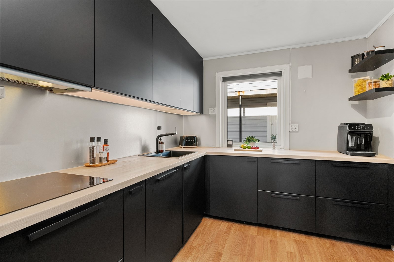 Innredningen er med glatte fronter, benkeplate med nedfelt oppvaskkum, integrerte hvitevarer og kjøkkenventilator over koketopp. Galleribilde