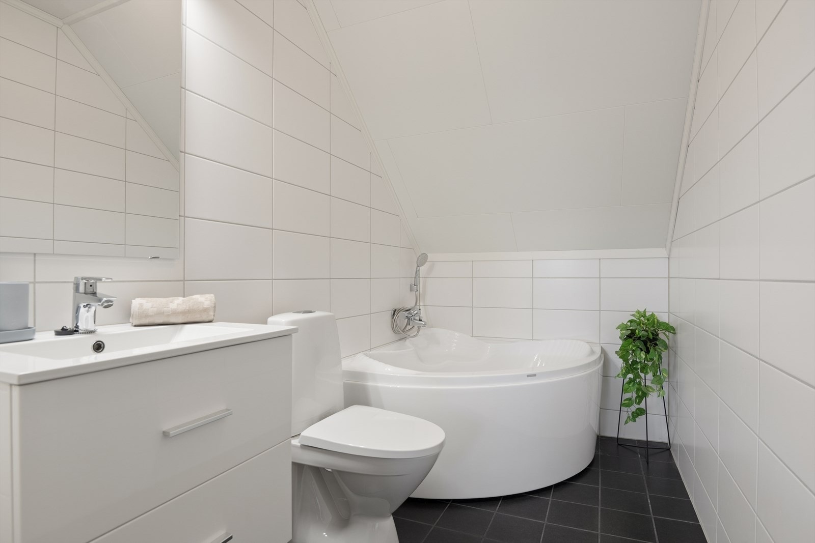 BaderomBadet i 2. etasje er utstyrt med baderomsinnredning med servant og ett-greps blandebatteri, WC, hjørnebadekar og veggmontert dusjbatteri. Galleribilde