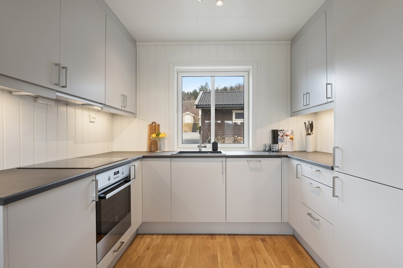 Kjøkkenet har en moderne innredning med grålakkerte, slette fronter på over- og underskap, laminerte skrog og laminert benkeplate. Galleribilde