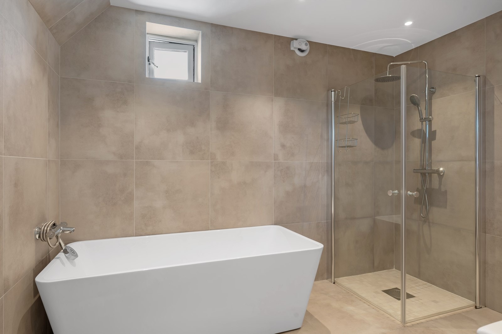 Lekkert bad med store fliser med varme i gulv samt badekar og dusjhjørne Galleribilde