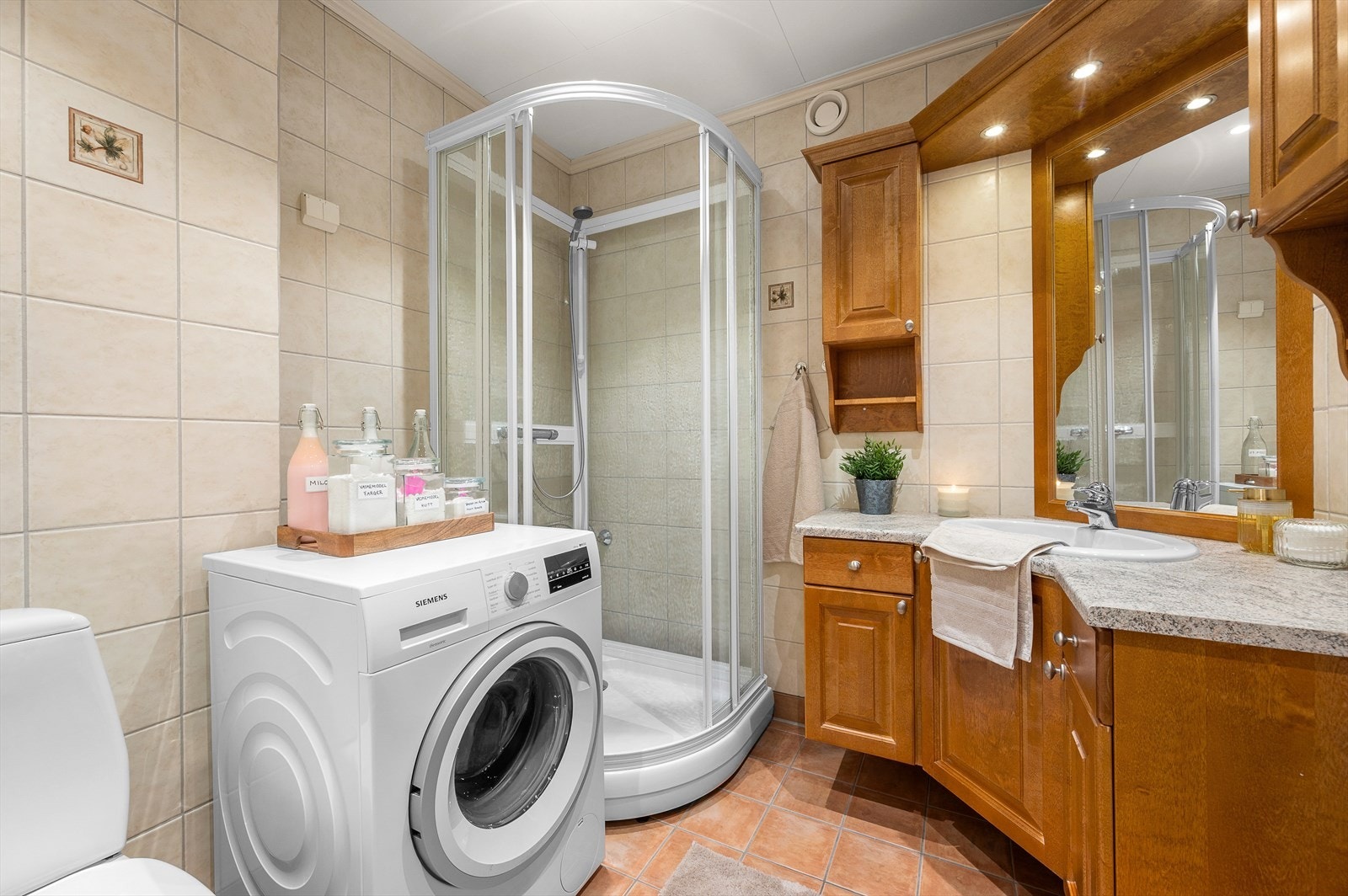 Flislagt vegg og gulv på bad med toalett, dusjkabinett, opplegg for vaskemaskin og praktisk servant. Det opplyses om at badet er oppgradert i perioden 2012. Her er det også behagelig varme i gulv. Galleribilde