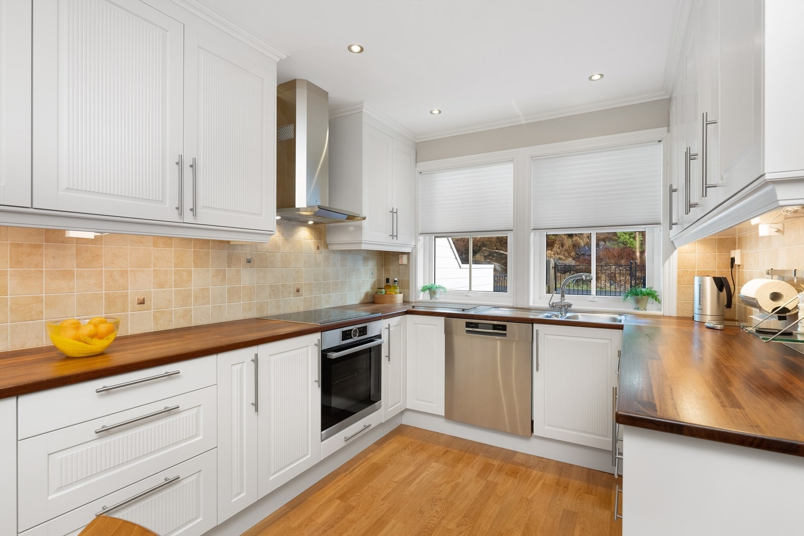 Pent kjøkken med hvite, profilerte fronter. Galleribilde