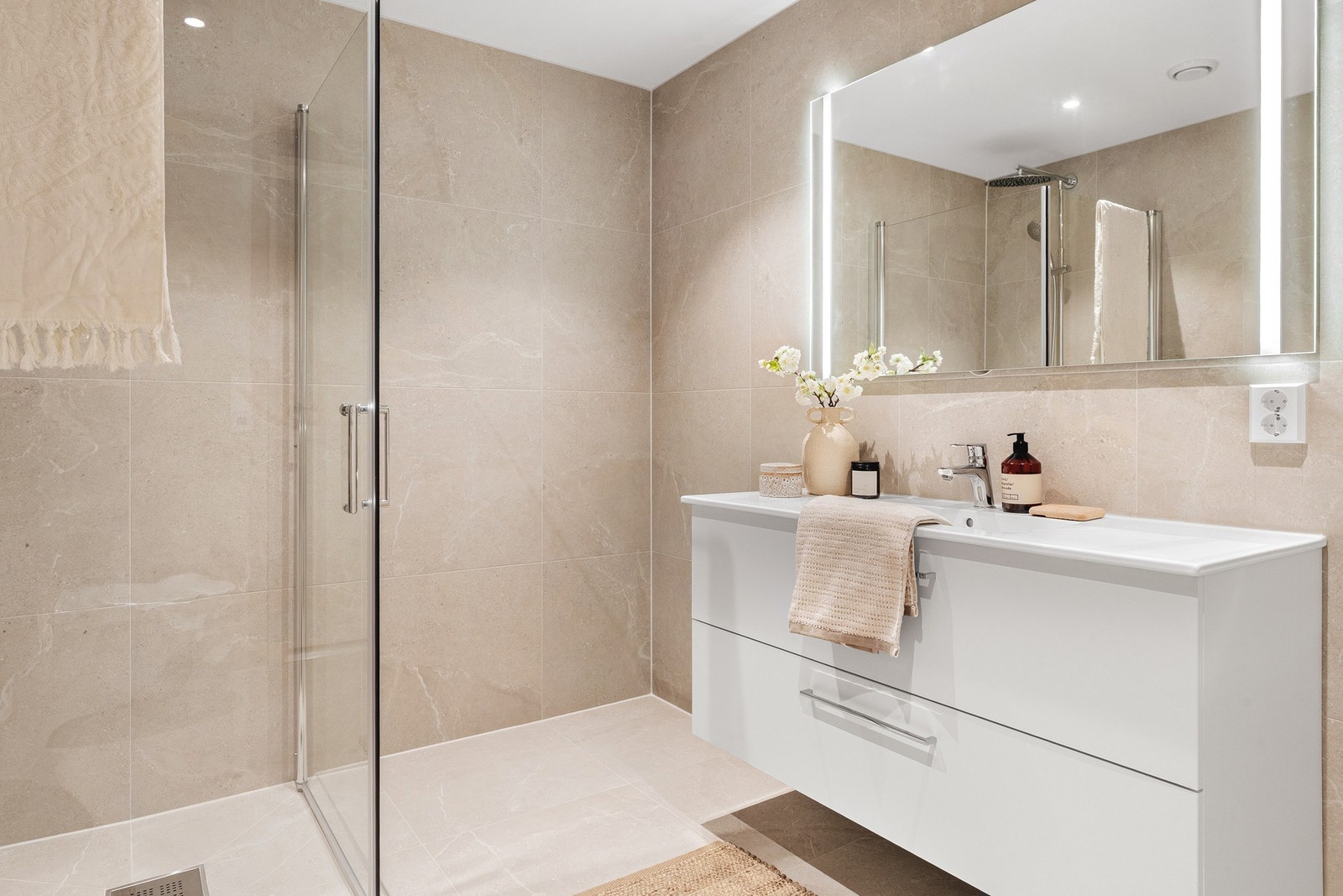 Badet er innredet med vegghengt toalett, servant med innredning og dusjhjørne. Galleribilde