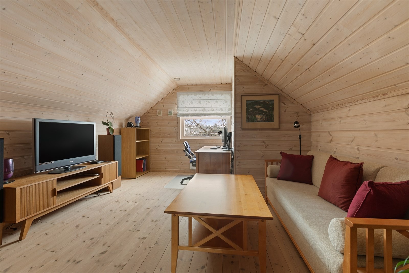 Det ene rommet på loftet er innredet som en ekstra stue. Overflater med panel og parkett. Galleribilde