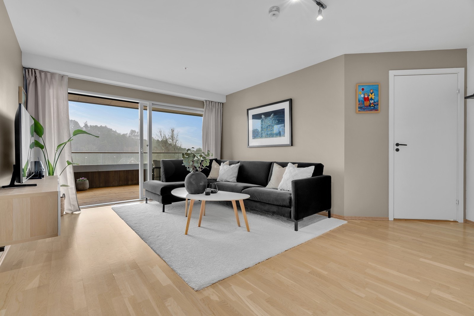 Leilighetens stue har store vindusflater og god plass til sofagruppe med tilhørende møblement Galleribilde