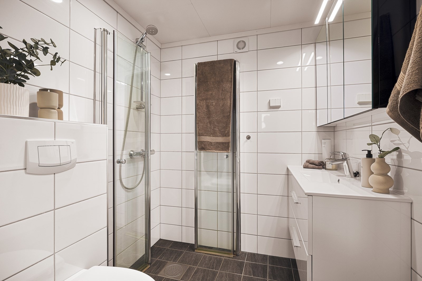 Badet er helfliset med elektriske varmekabler i gulvet og er utstyrt med vegghengt toalett og dusjhjørne med dører. Galleribilde