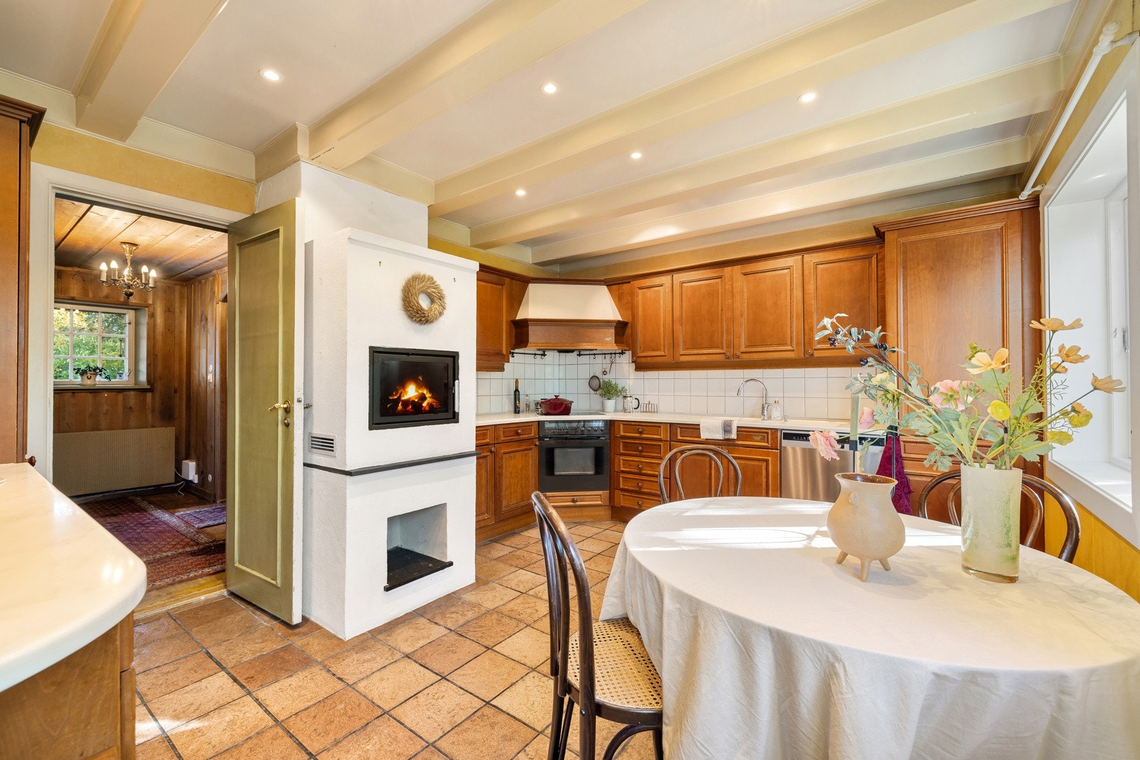 Romslig kjøkkenrom med innredning i kirsebær fra Sivesind. Det er flotte gulvfliser, rentbrennende ildsted og innfelte downlights i himlingen. Galleribilde