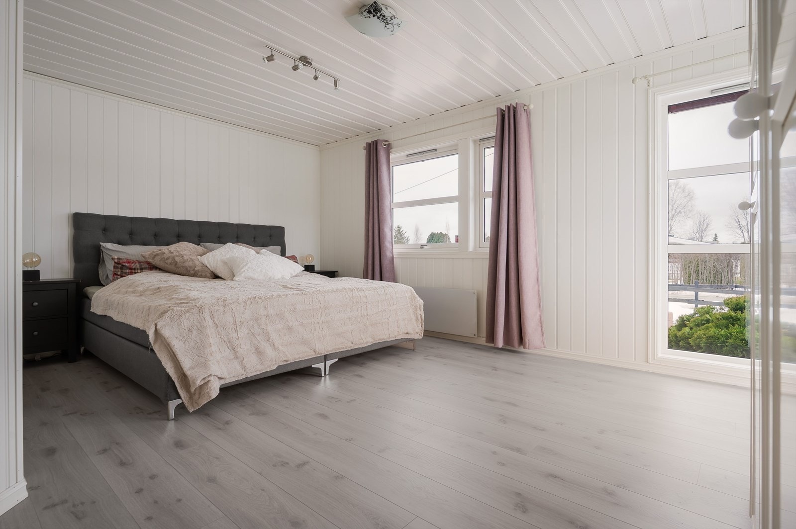 Stort og lyst hovedsoverom som ligger i tilbygget del fra 1997. Soverommet har lys enstavs laminat på gulv og lyse panelplater på veggene. Galleribilde