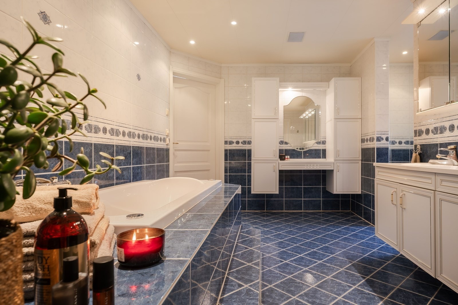 Lys baderomsinnredning med heldekkende dobbel servant, flere speilskap med belysning over. Galleribilde