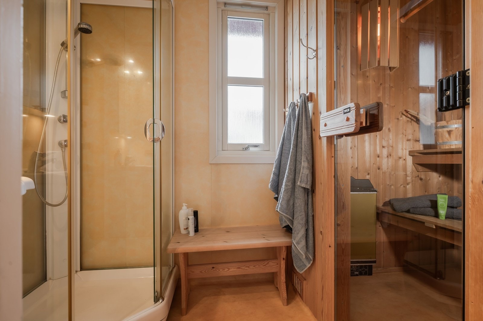 Vegg-i-vegg med toalettrommet er det et baderom med vinylbelegg på gulv med gulvvarme og baderomsplater på veggene. Fra baderommet er det adkomst til en deilig badstue med plassbygde sittebenker og badstueovn. Galleribilde