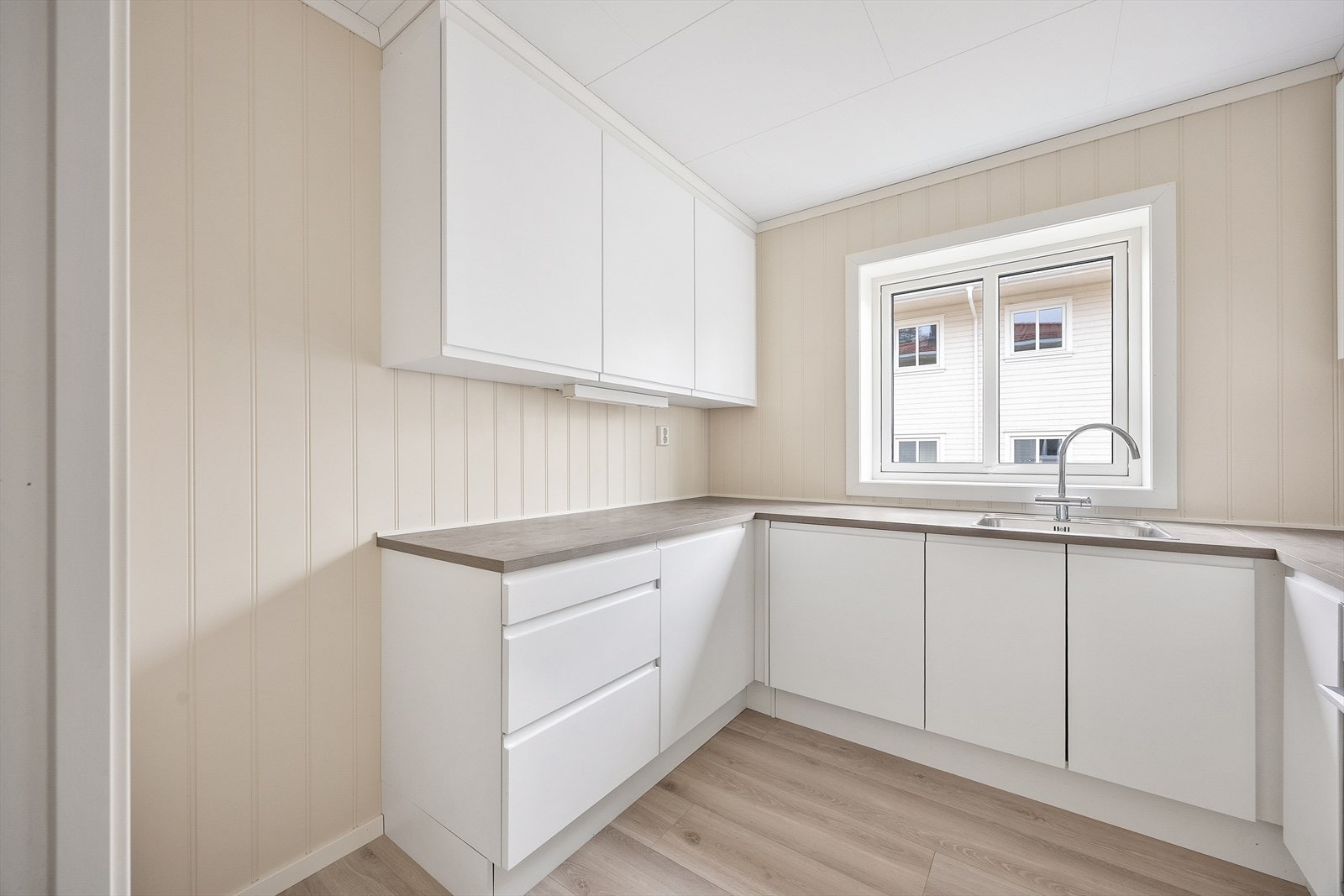 Takhøye overskap med glatte, hvite fronter gir optimal utnyttelse av plassen. Galleribilde