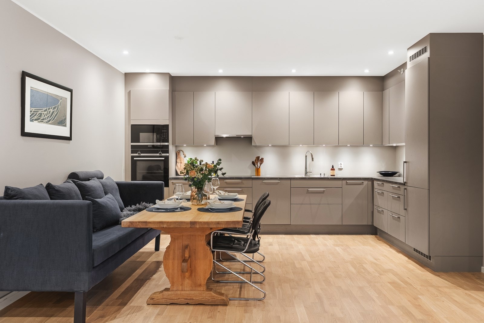 Lekker kjøkkeninnredning med beige fronter, benkeplate i laminat og integrerte hvitevarer. Galleribilde