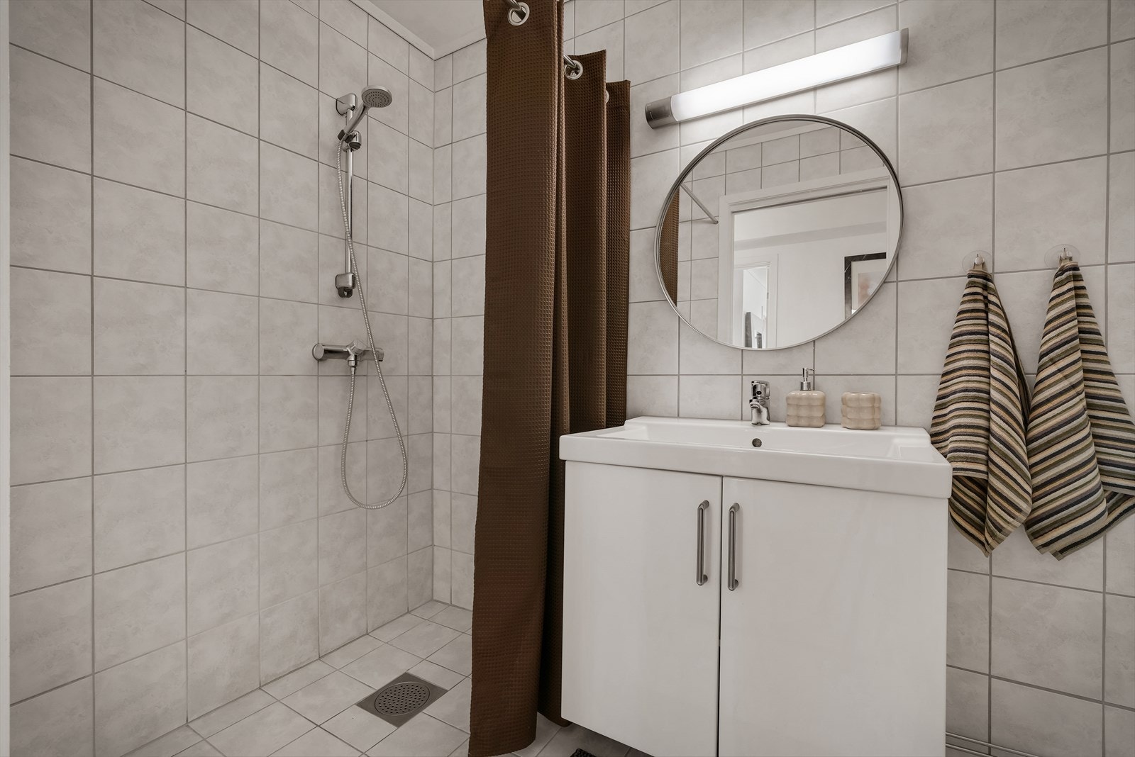 Badet er innredet med baderomsskap, nedfelt servant, speil og dusj. Galleribilde