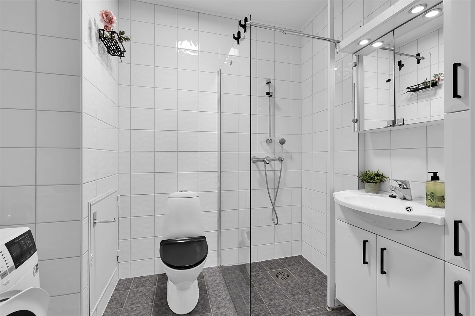 Badet byr på delikat dusjnisje med glassvegger, opplegg for vaskemaskin og rikelig oppbevaringsplass i skap. Galleribilde