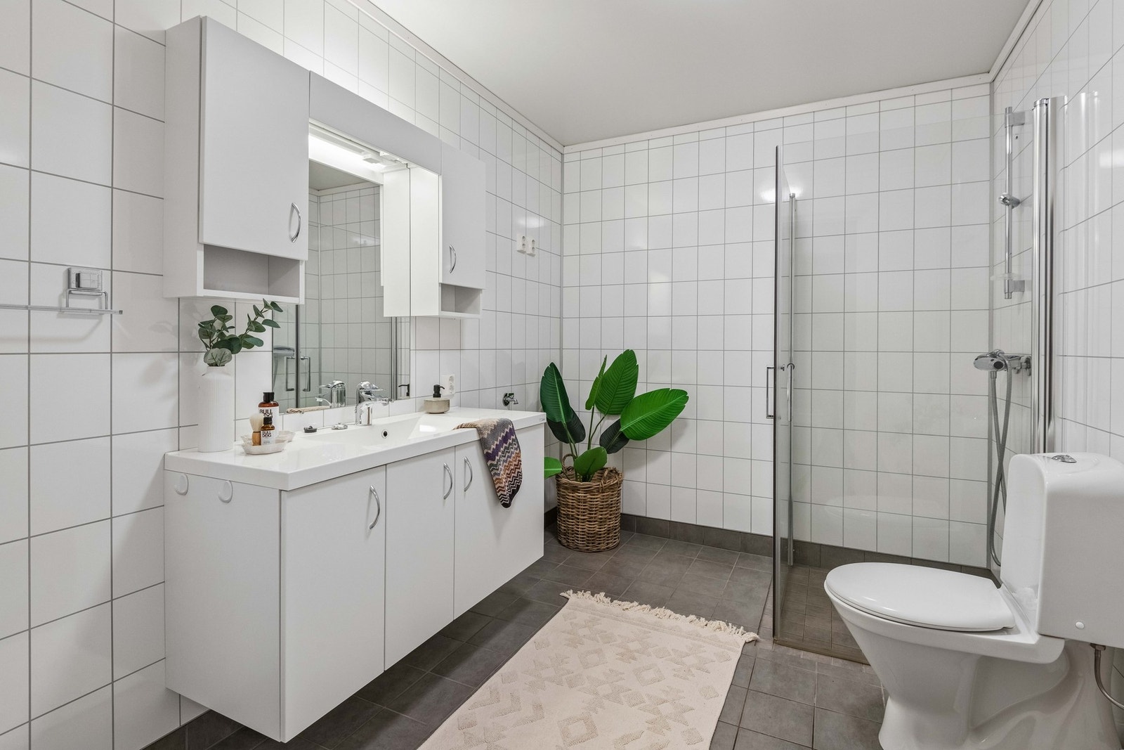 Badet har flislagt gulv og varmekabler. Praktisk dusjhjørne med glassdører og en romslig baderomsinnredning. Galleribilde