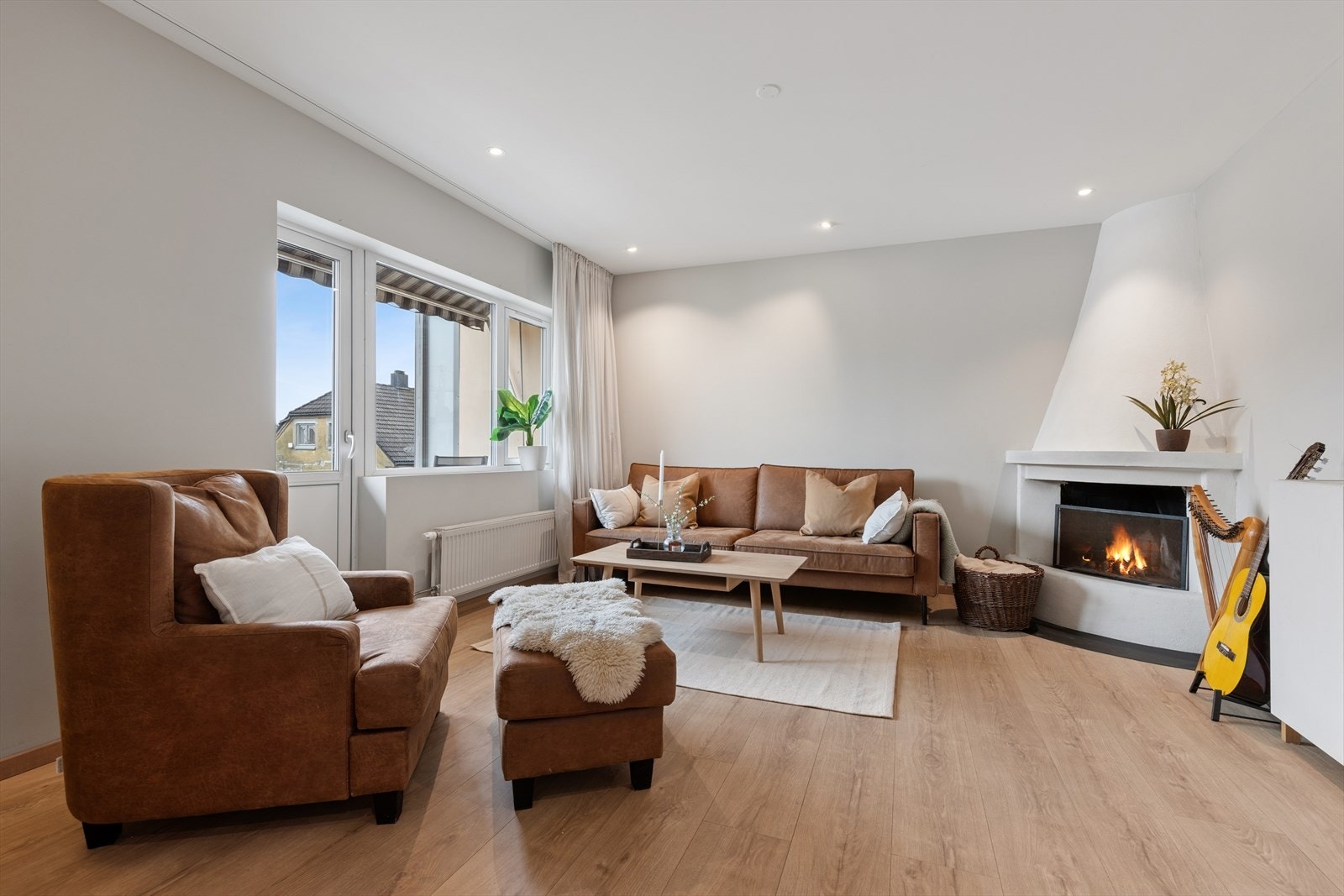 Stuen er lys og innbydende med spotter i himlingen som gir en moderne atmosfære. En murt, åpen peis fungerer som et trivelig samlingspunkt i rommet Galleribilde