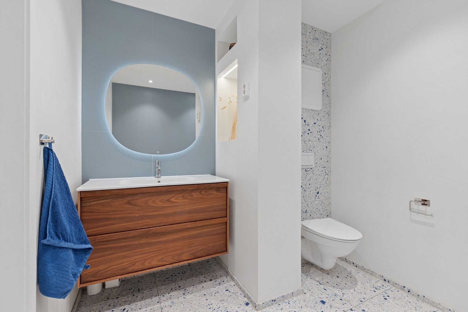 Rommet er utstyrt med baderomsmøbel med servant, badekar, vegghengt toalett og opplegg for vaskemaskin. Varmekabler i gulvet gir ekstra komfort, og mekanisk avtrekk sikrer et godt inneklima. Galleribilde