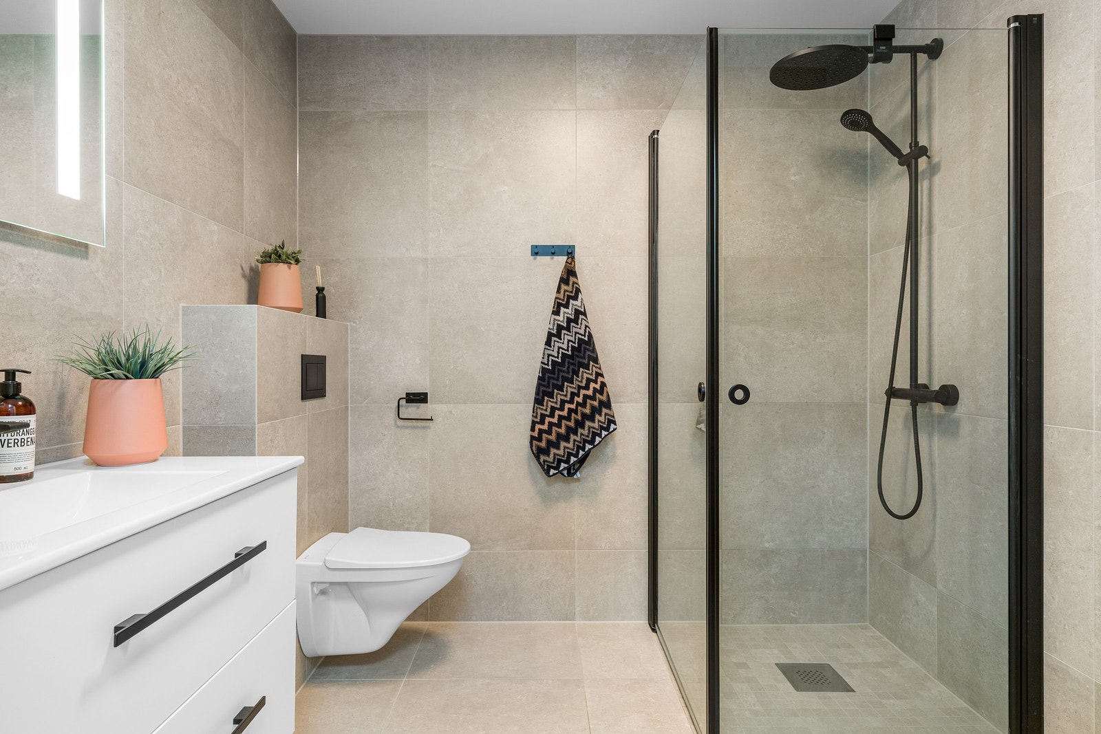 Badet i andre etasje er helfliset med 60 x 60 fliser på både vegg og gulv, og fremstår som gjennomført med stilrene, svarte detaljer. Galleribilde