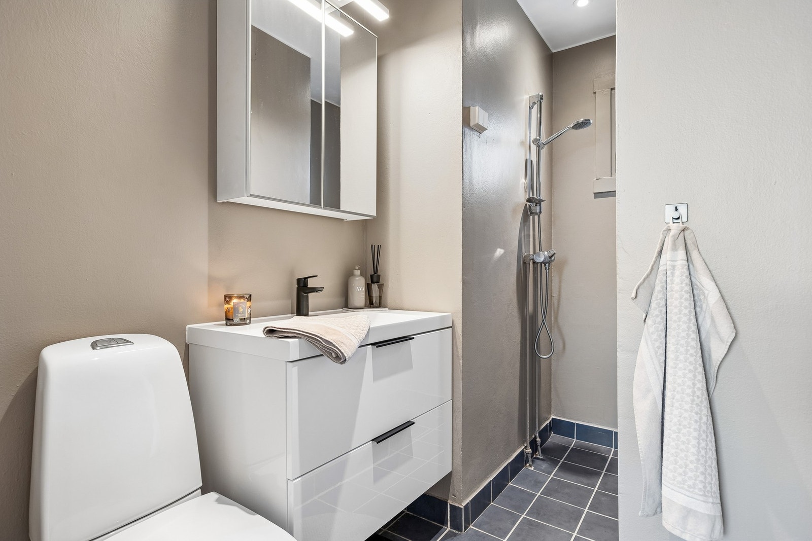 Badet er innredet med vegghengt servantinnredning, speilskap med overlys, dusjsone og toalett. Galleribilde