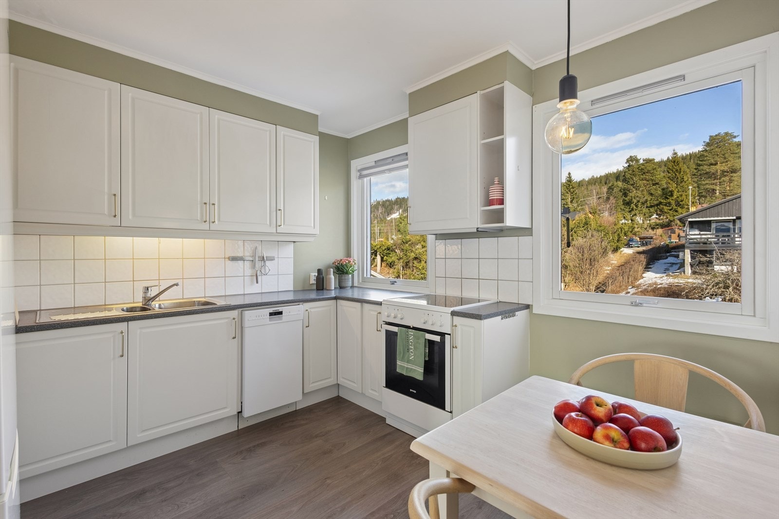 Kjøkkenet er stilrent innredet med hvite, profilerte fronter og grå benkeplate i laminat. Et romslig kjøkken som gir godt med skap- og skuffeplass, samt gode arbeidsflater på benk. Galleribilde