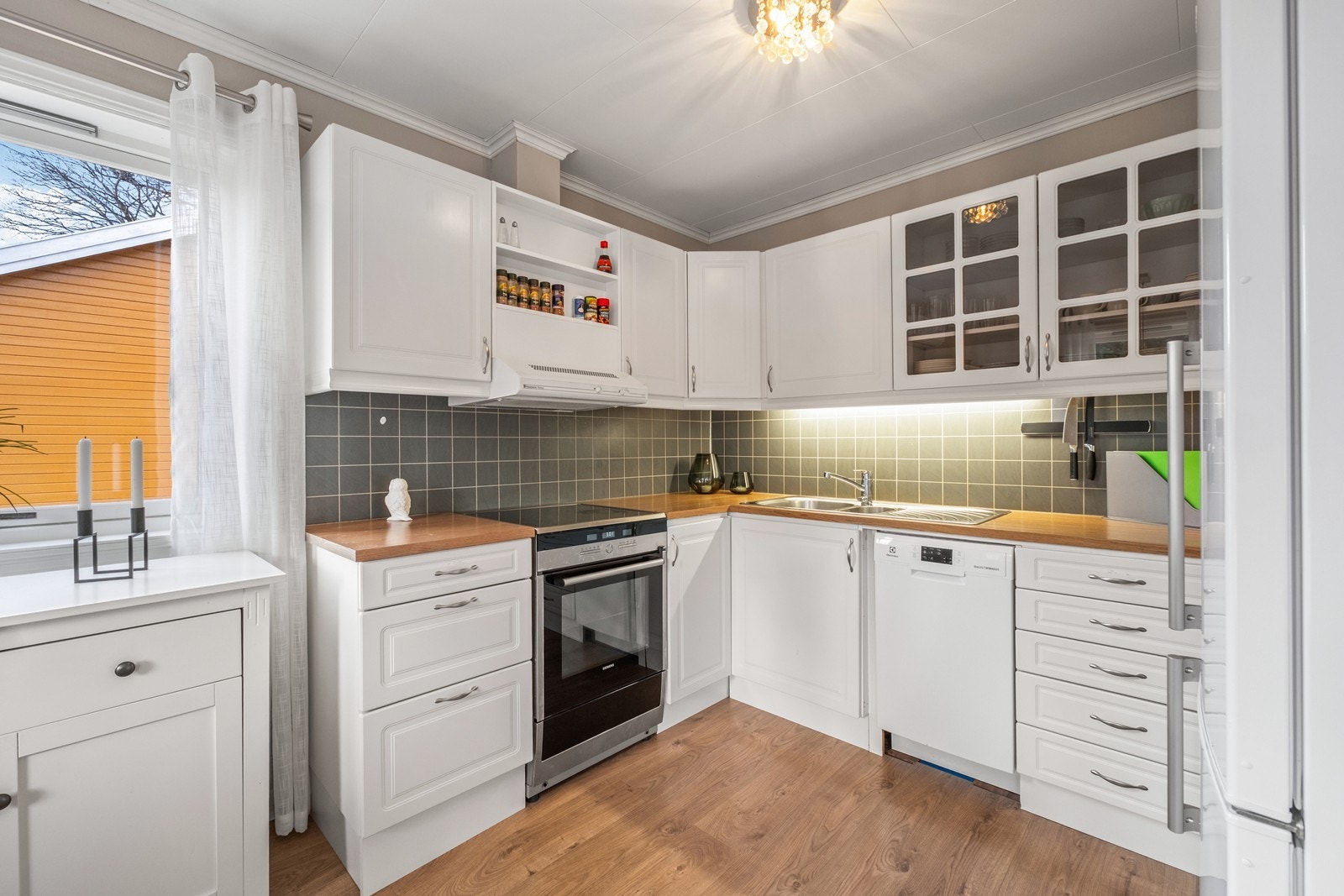 Kjøkkenet er utstyrt med hvit, tidløs kjøkkeninnredning med profilerte fronter og opplegg til frittstående hvitevarer. Galleribilde